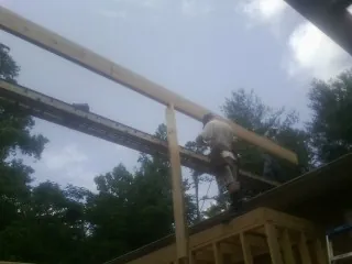 Carpenter setting a ridge beam over a new addition frame — Ice Dam Removal by Roofing Brothers in Biglerville