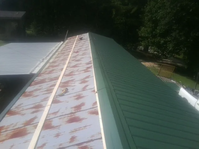 Old rusted panels beside newly installed green metal roofing — Wind Damage Roof Repair by Roofing Brothers in Biglerville