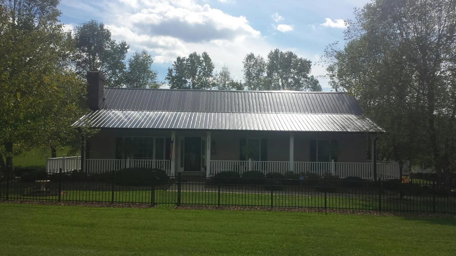 Gray metal roof on a brick ranch with a full width front porch — Gutter Guard Installation work by our crew in Biglerville