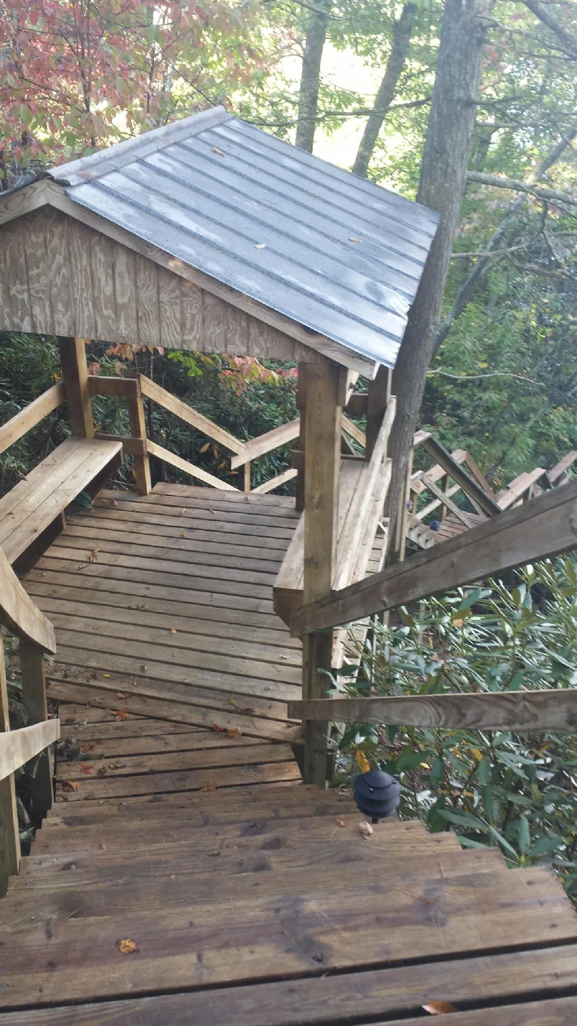 Metal roofed shelter over wooden steps on a wooded walkway — Skylight Repair & Installation work by our crew in Biglerville