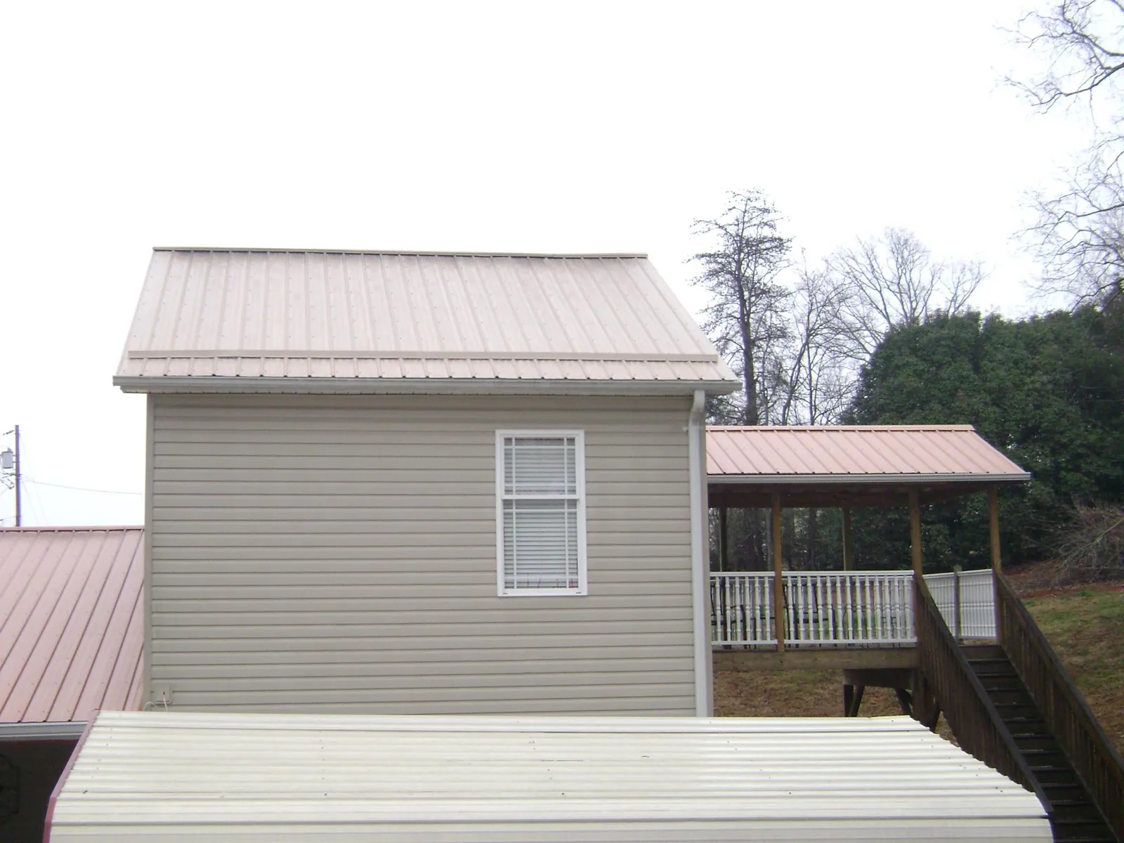 Tan metal roofs on a two story addition and attached porch, from a Roof Replacement job in Biglerville