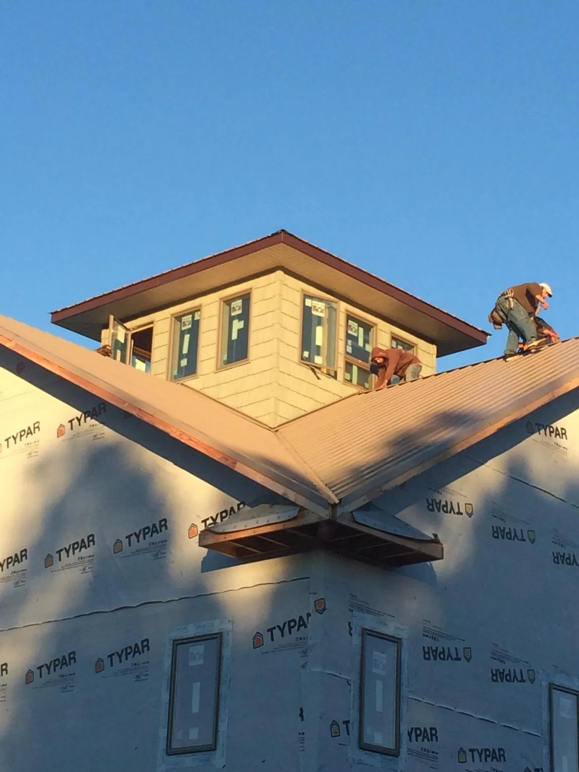Roofers working around a rooftop cupola on a new metal roof at sunset — Roof Waterproofing in Biglerville by Roofing Brothers